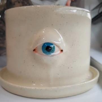 A speckled white planter with a single blue eye